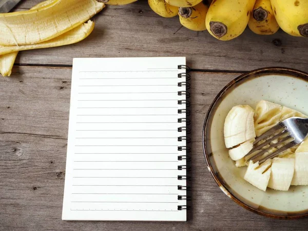 Ahşap arka plan üzerinde boş not defteri ile püre muz