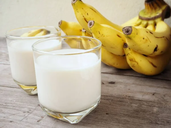 Fresh milk with bananas on old wooden background