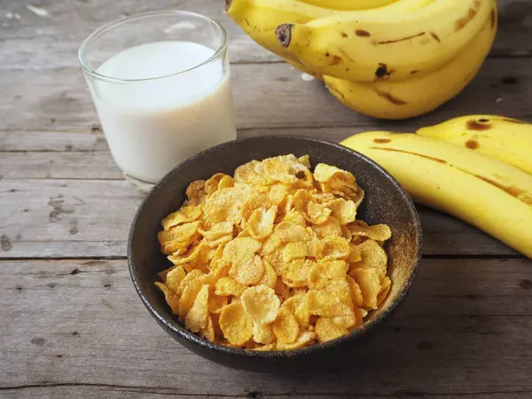 Mısır gevreği ahşap arka plan üzerinde muz ile servis görünümü Kapat