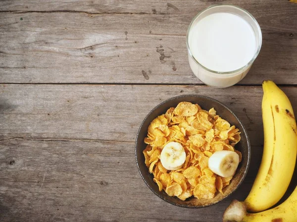 Mısır gevreği süt ve muz ahşap arka plan üzerinde üstten görünüm