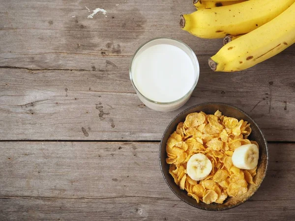 Mısır gevreği süt ve muz ahşap arka plan üzerinde üstten görünüm