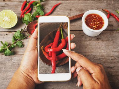 Fotoğraf geleneksel Tay tatlı kırmızı biber çorbası smartphone ile ahşap arka plan üzerinde çekici.