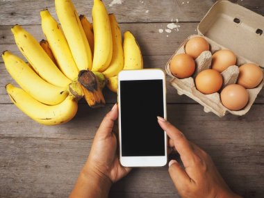 Yumurta ve muz ile akıllı telefon kullanan kadın