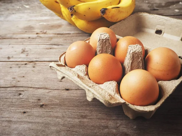 Huevos y plátanos sobre fondo de madera — Foto de Stock