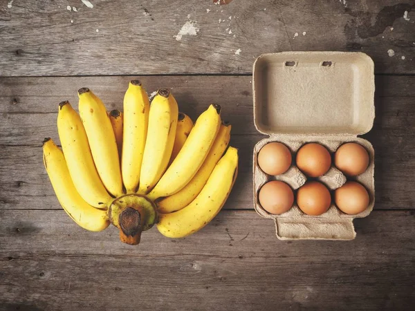 Huevos y plátanos sobre fondo de madera — Foto de Stock