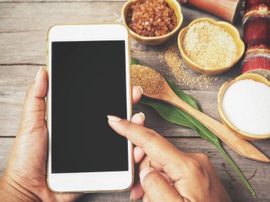 Pişirme sırasında boş ekran ile akıllı telefon kullanan kadın kırpılmış atış