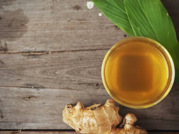 Zencefil çayı zencefil kökü ve ahşap zemin üzerine yeşil yaprakları ile