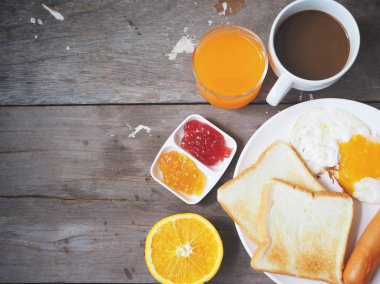 Yumurtayla sosis ve tost ekmeği ahşap masa üzerinde reçelli kahvaltı