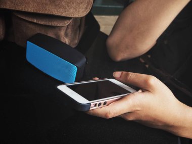 Bluetooth hoparlör ile akıllı telefon kullanan kadın