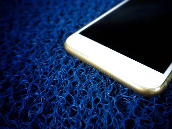 蓝色塑料背景上的白色智能手机 — 图库照片