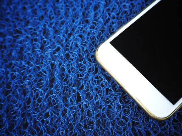 蓝色塑料背景上的白色智能手机 — 图库照片