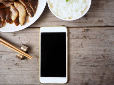 Kızarmış domuz eti ve ahşap zemin üzerine pişmiş pirinç ile Smartphone