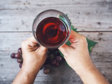 Ahşap arka plan üzerinde bardak taze üzüm suyu tutan kadın