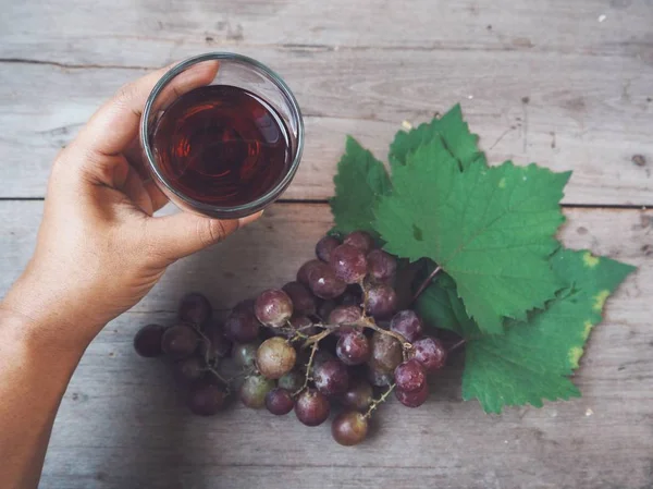 Ahşap arka plan üzerinde bardak taze üzüm suyu tutan kadın
