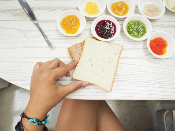 Woman eating bread with different kinds of fruit jam