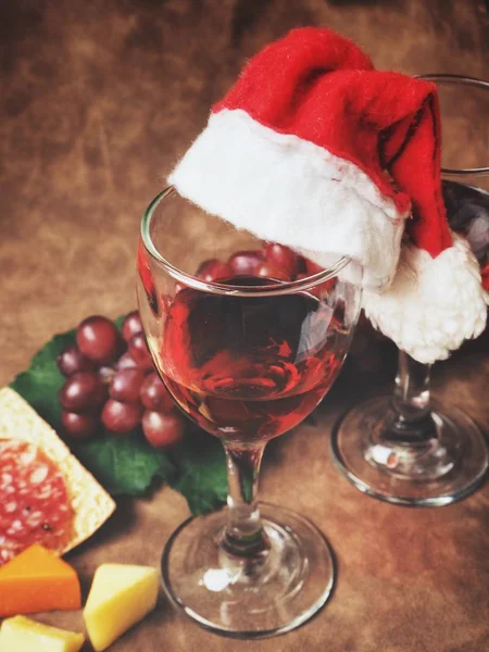 Vinho tinto com salsichas de queijo e chapéu de Natal — Fotografia de Stock