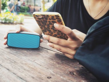 Bluetooth hoparlör ile akıllı telefon kullanan kadın
