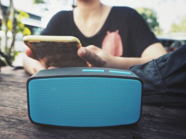 Bluetooth hoparlör ile akıllı telefon kullanan kadın