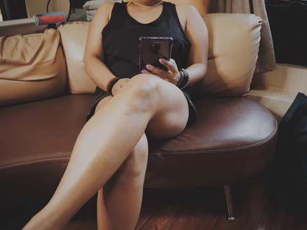 Kvinna som använder Smart telefon till hands i soffan — Stockfoto