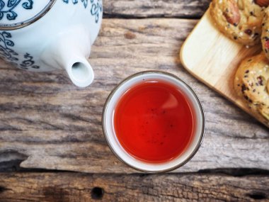 Çay gülü ve demlik ahşap arka planda