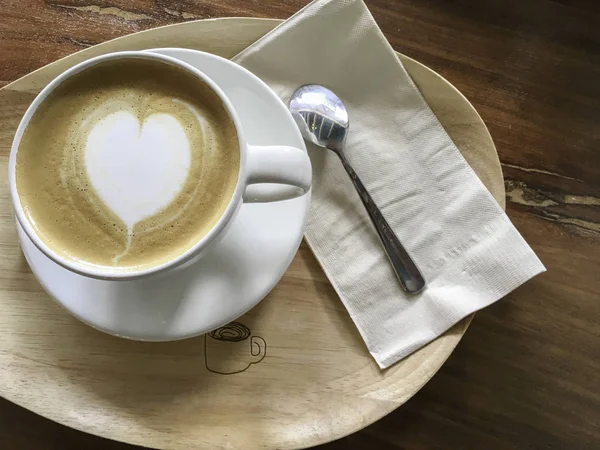 Vit kopp hjärta form cappuccino kaffe på trä platta — Stockfoto