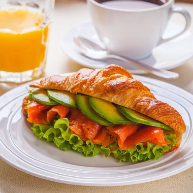 kruvasan sandviç somon ve avokado, kahve ve portakal suyu üzerinde beyaz bir arka plan ile