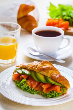 kruvasan sandviç somon ve avokado, kahve ve portakal suyu üzerinde beyaz bir arka plan ile