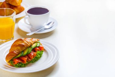 kruvasan sandviç somon ve avokado, kahve ve portakal suyu üzerinde beyaz bir arka plan ile