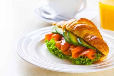 kruvasan sandviç somon ve avokado, kahve ve portakal suyu üzerinde beyaz bir arka plan ile