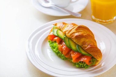 kruvasan sandviç somon ve avokado, kahve ve portakal suyu üzerinde beyaz bir arka plan ile