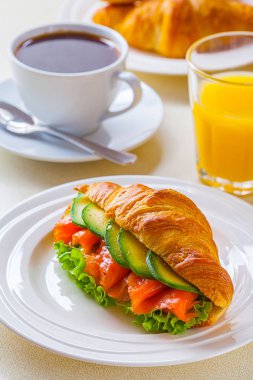 kruvasan sandviç somon ve avokado, kahve ve portakal suyu üzerinde beyaz bir arka plan ile