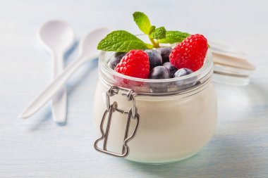 Ahududu, yaban mersini ve cam mavi bir arka plan üzerine nane ile yoğurt