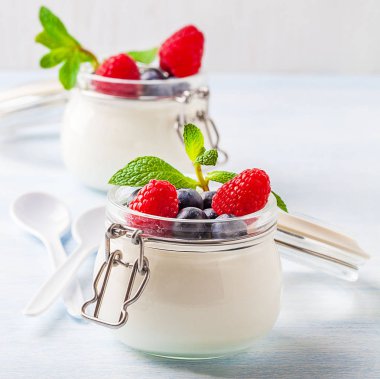 Ahududu, yaban mersini ve cam mavi bir arka plan üzerine nane ile yoğurt