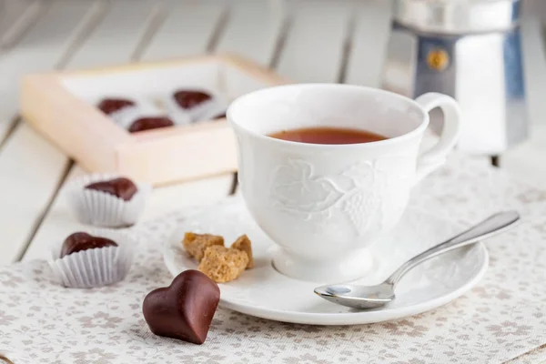 Чай в белой чашке с шоколадными конфетками — стоковое фото