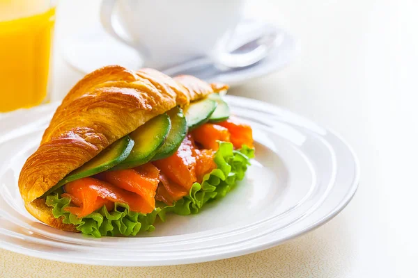Panino croissant con salmone e avocado, caffè e succo d'arancia su fondo bianco — Foto Stock