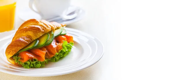 Panino croissant con salmone e avocado, caffè e succo d'arancia su fondo bianco — Foto Stock