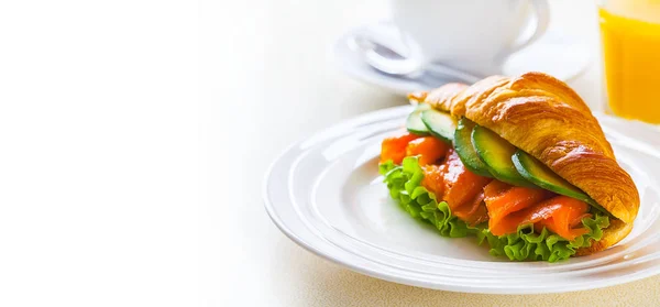 Panino croissant con salmone e avocado, caffè e succo d'arancia su fondo bianco — Foto Stock