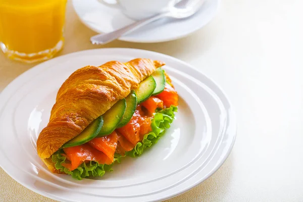 Panino croissant con salmone e avocado, caffè e succo d'arancia su fondo bianco — Foto Stock