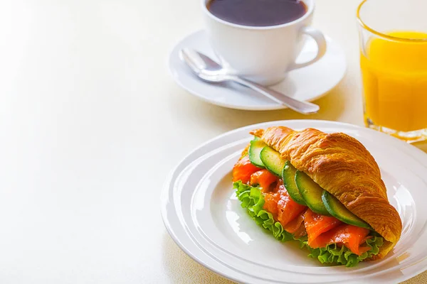 Croissant sandwich with salmon and avocado, coffee and orange juice on a white background — Stock Photo, Image