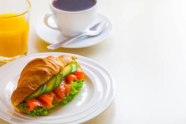 Panino croissant con salmone e avocado, caffè e succo d'arancia su fondo bianco — Foto Stock