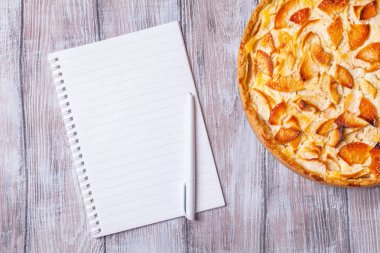 Apple pie, defter notları, tükenmez kalem gri bir arka plan üzerinde yatay olarak