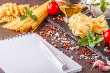 Yatay olarak yazmak, boşaltmak için bir not defteri ile mozzarella ve domates karanlık bir arka plan ile makarna için malzemeler