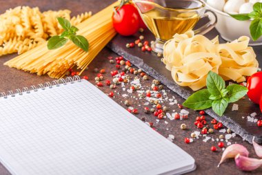 Yatay olarak yazmak, boşaltmak için bir not defteri ile mozzarella ve domates karanlık bir arka plan ile makarna için malzemeler