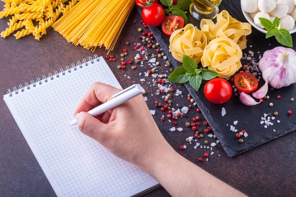 Ingredientes para massas com mussarela e tomates em um fundo escuro, horizontalmente com um bloco de notas para escrever — Fotografia de Stock