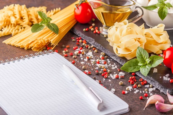 Ingredientes para pasta con mozzarella y tomates sobre fondo oscuro, horizontalmente con bloc de notas para escribir, copyspace —  Fotos de Stock