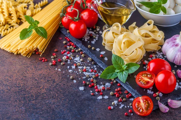 Ingredientes para pasta con mozzarella y tomates sobre fondo oscuro, horizontalmente, copyspace —  Fotos de Stock
