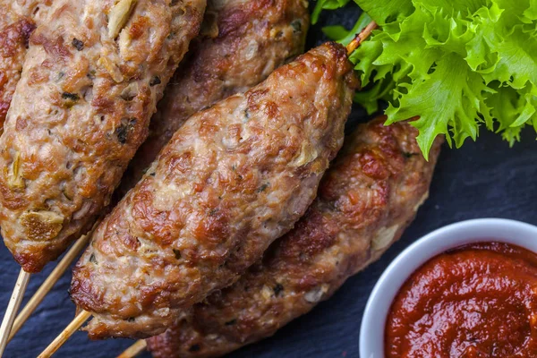 Lulya-kebab. Shish kebab su un bastone, carne macinata. Piatto tradizionale caucasico. Con insalata verde, ketchup, spezie . — Foto Stock