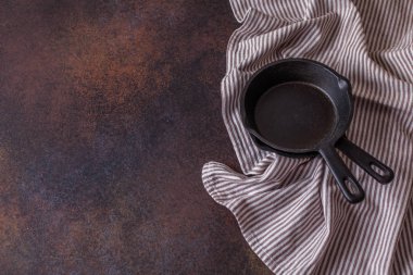 karanlık bir arka plan üzerine bir havlu ile siyah dökme demir tava