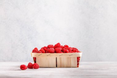 hafif ahşap arka plan üzerinde yatay bir hasır sepet içinde ahududu