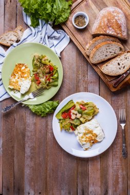 dikey olarak ahşap bir arka plan üzerinde renkli sebze salatası ile omlet tabaklar